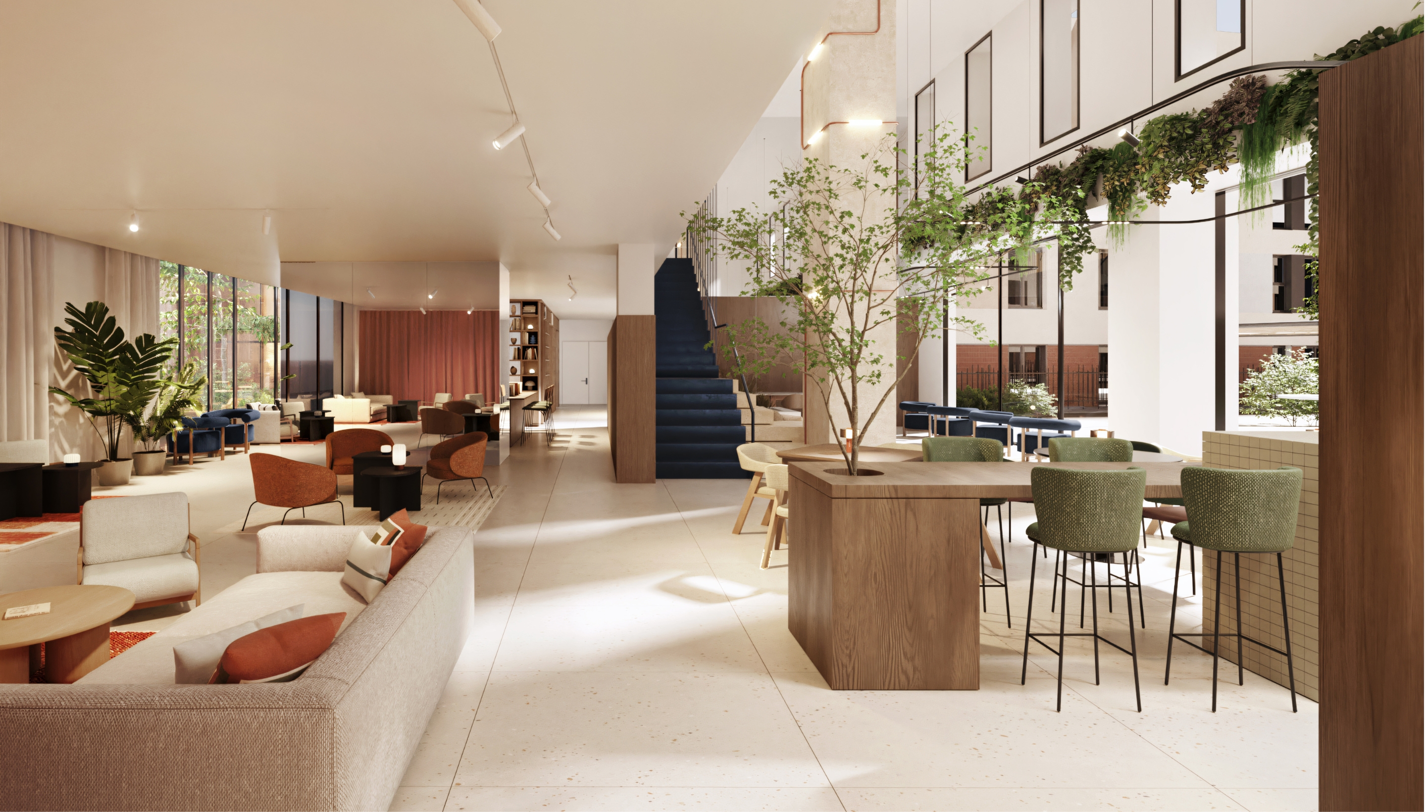Sala común en Calido Living con diseño moderno, mesas, sillas y plantas decorativas, iluminada con luz natural.