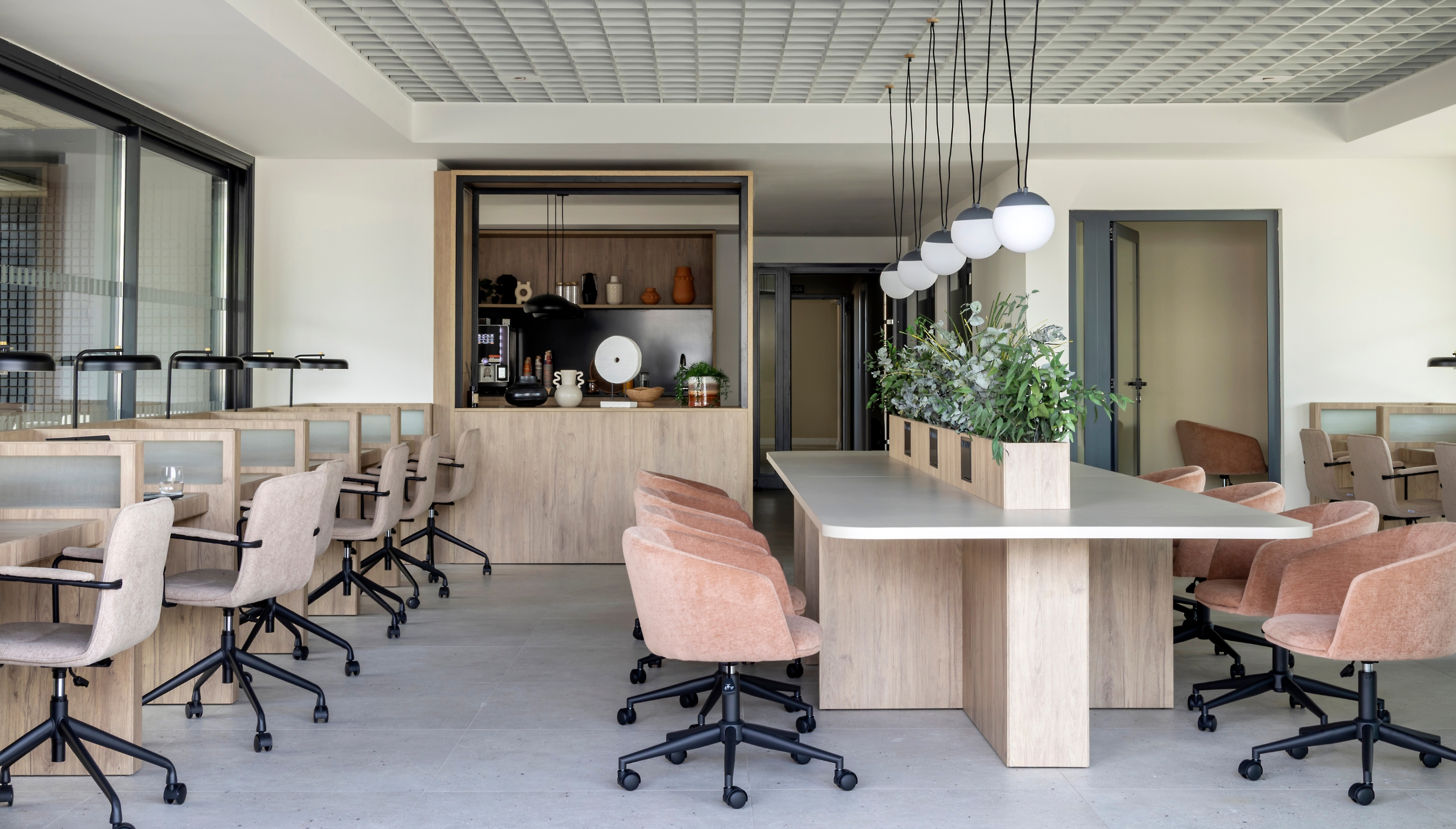 Sala de coworking elegante y moderna con mesas compartidas y estanterías llenas de libros en Calido Living Alcobendas.