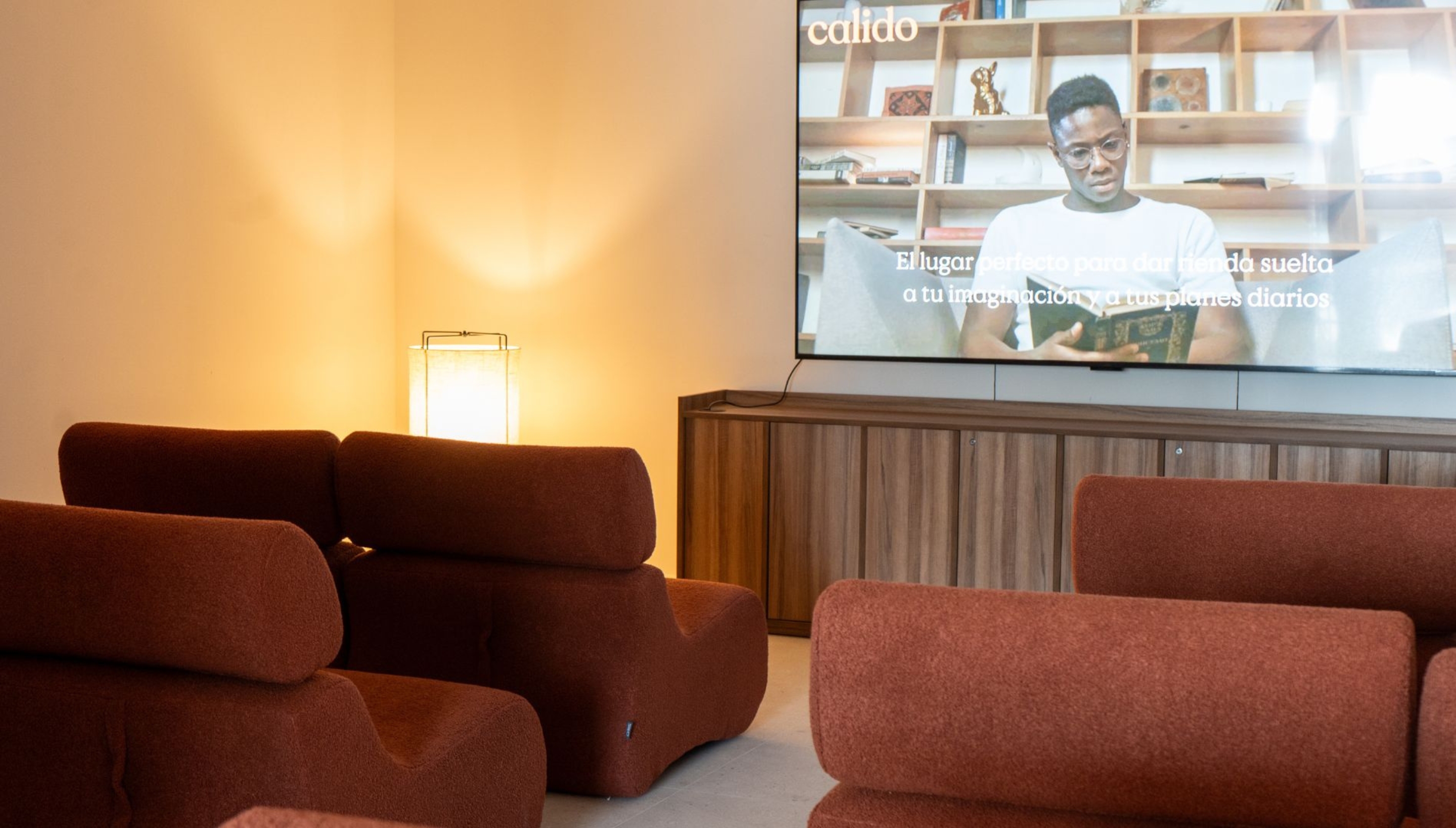 Área de proyección y entretenimiento con asientos cómodos y pantalla grande en Calido Living.