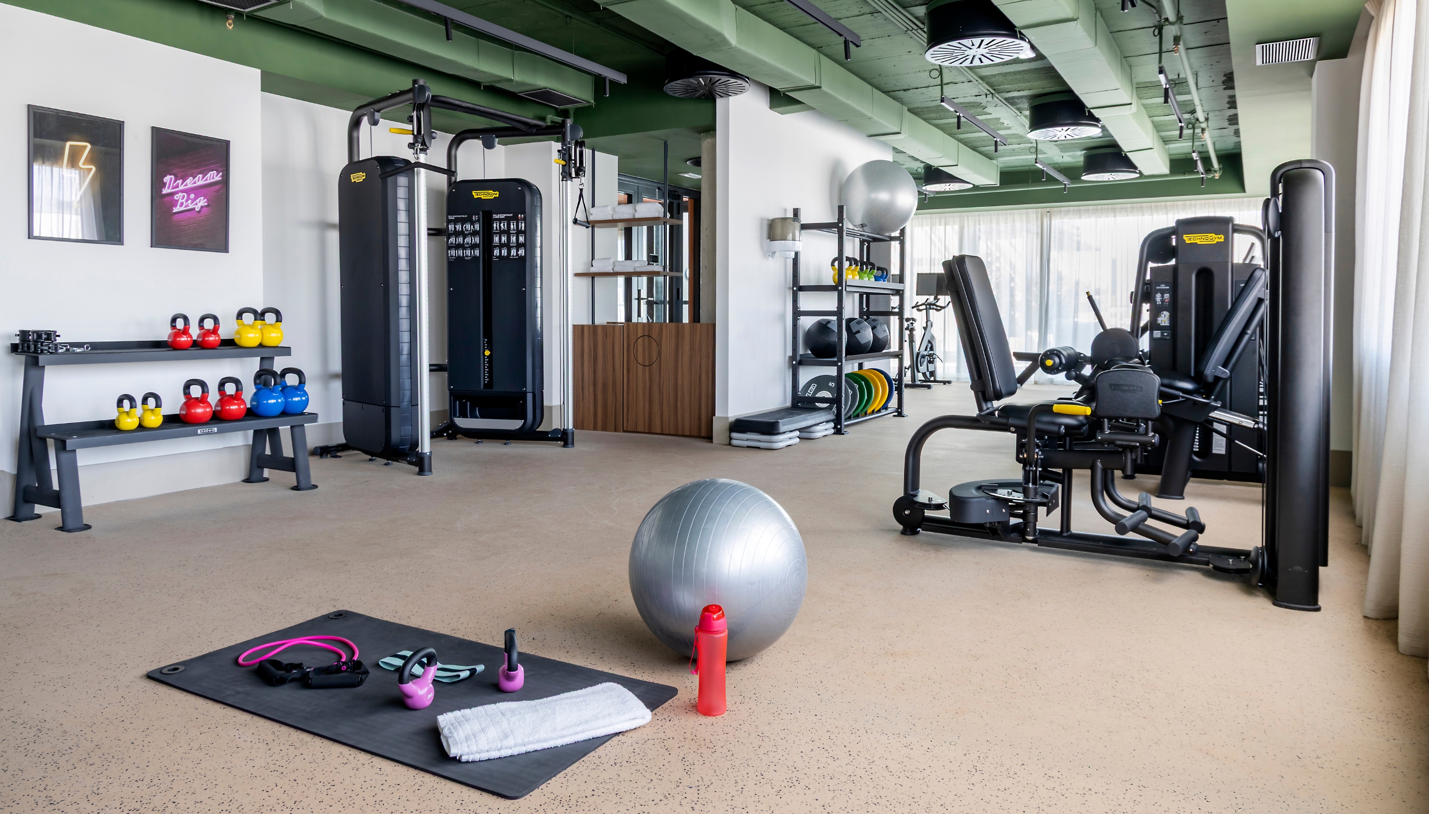 Sala de gimnasio moderna en Calido Living, equipada con máquinas de ejercicio, pesas y accesorios para entrenamientos personalizados.