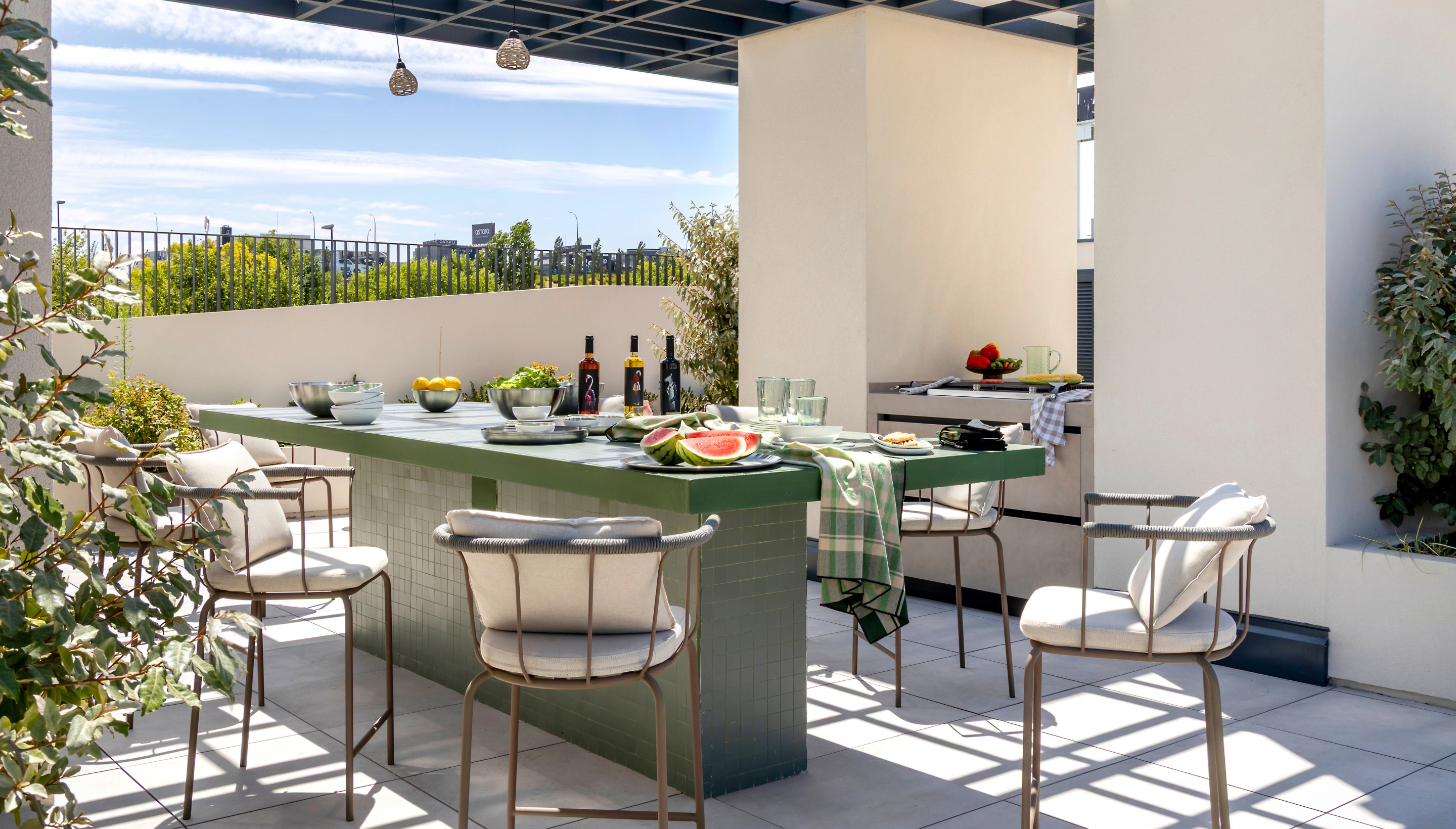 Terraza exterior en Calido Living, decorada con sofás cómodos, cojines y vegetación, ideal para momentos de relax al aire libre.