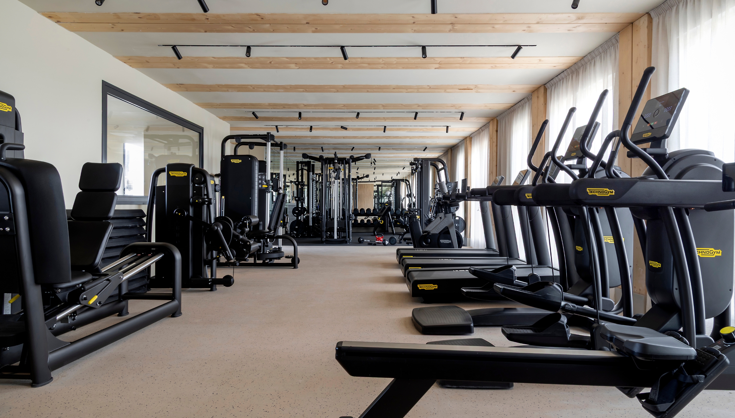 Sala de gimnasio moderna en Calido Valdebebas, equipada con máquinas de ejercicio, pesas y accesorios para entrenamientos personalizados.