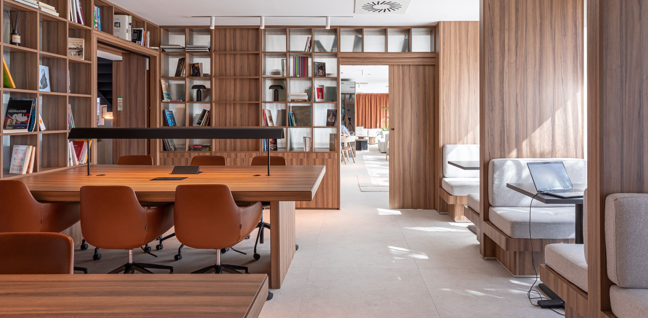 Sala de coworking elegante y moderna con mesas compartidas y estanterías llenas de libros en Calido Living Alcobendas.