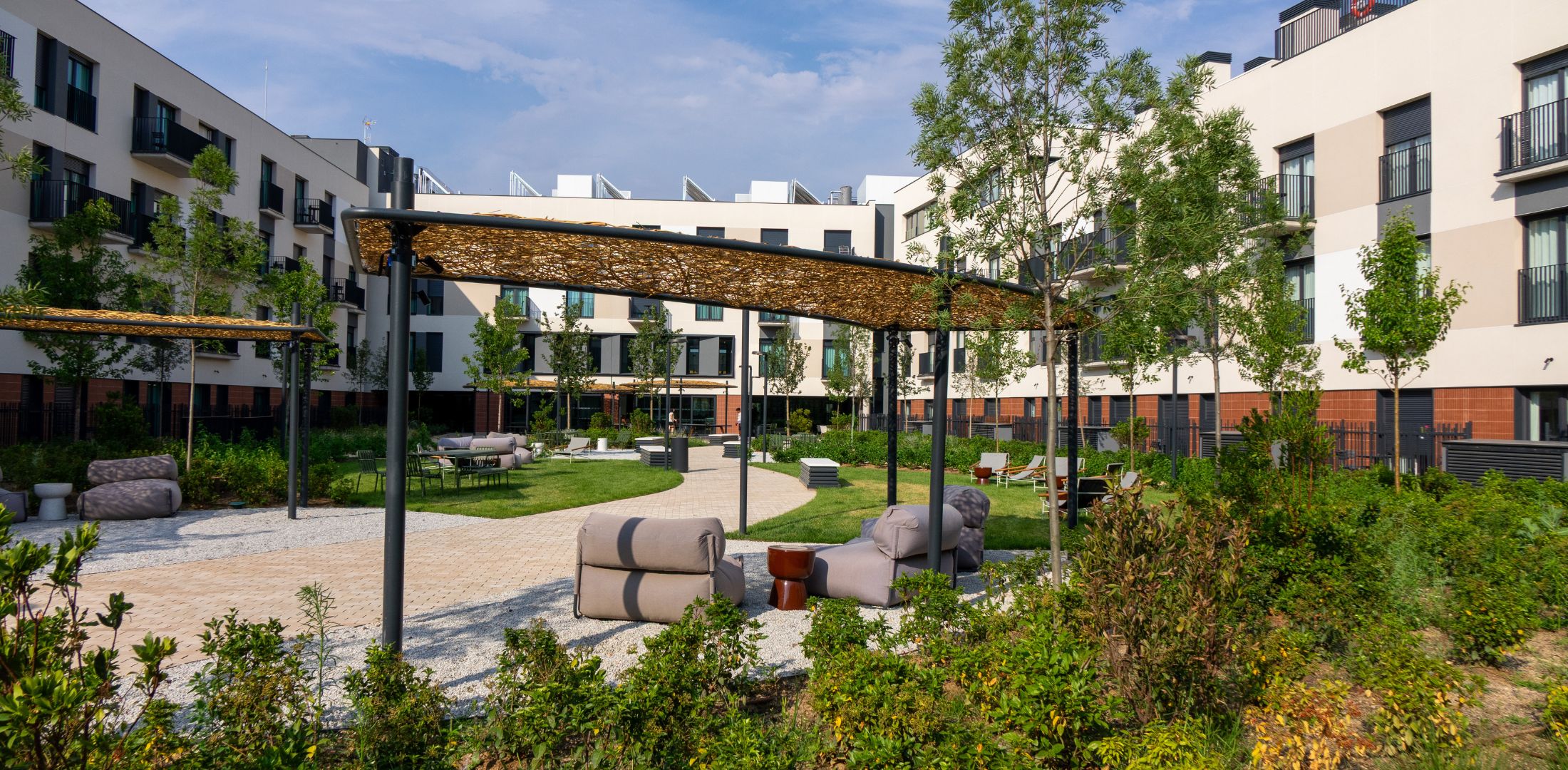 Jardín central al aire libre con áreas para sentarse y relajarse, rodeado de apartamentos en Calido Living.