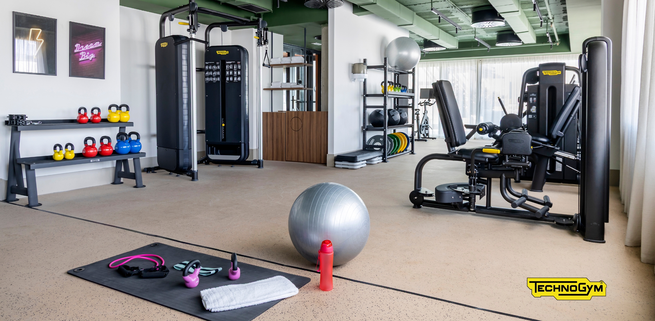 Sala de gimnasio moderna en Calido Living, equipada con máquinas de ejercicio, pesas y accesorios para entrenamientos personalizados.