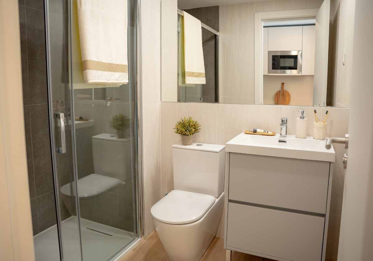 Baño completo en un estudio de Calido Living con ducha moderna, lavabo y decoración minimalista.
